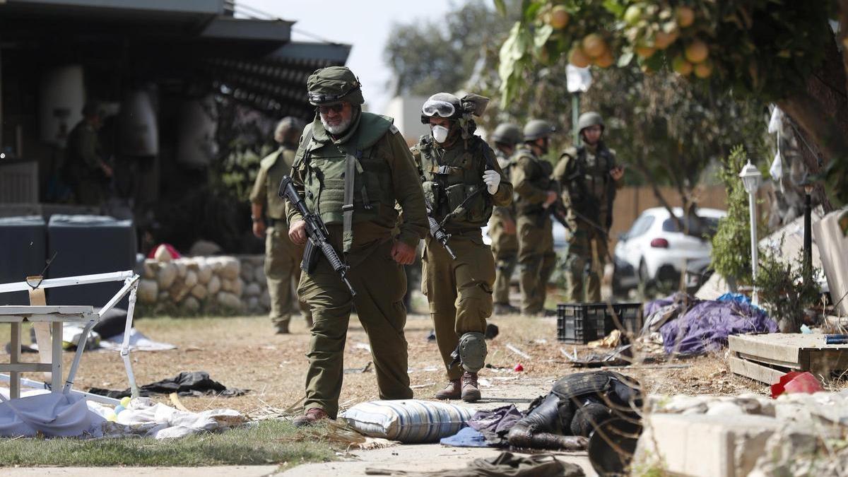 Soldats israelians caminen al costat de cadàvers de milicians d'Hamàs al quibuts Kfar Aza, aquest dimarts