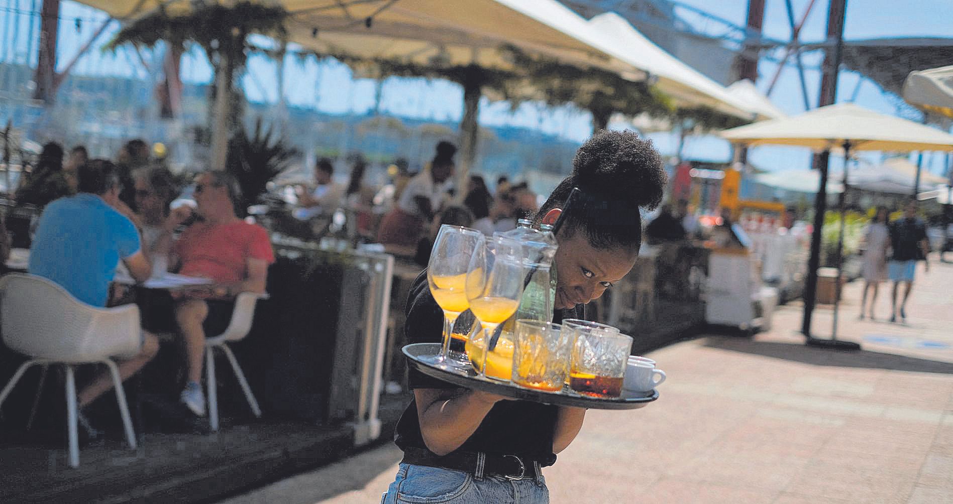 A waitress removes drinks from a table in a restaurant in Lisbon, Portugal, June 6, 2022. Picture taken June 6, 2022. REUTERS/Pedro Nunes