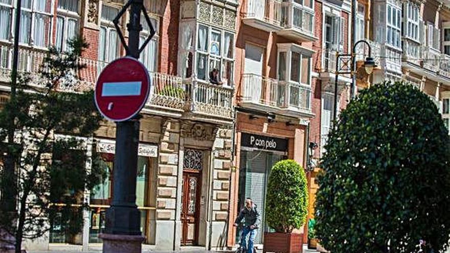 Una persona en bici pasa debajo de un balcón con un vecino en Cartagena.