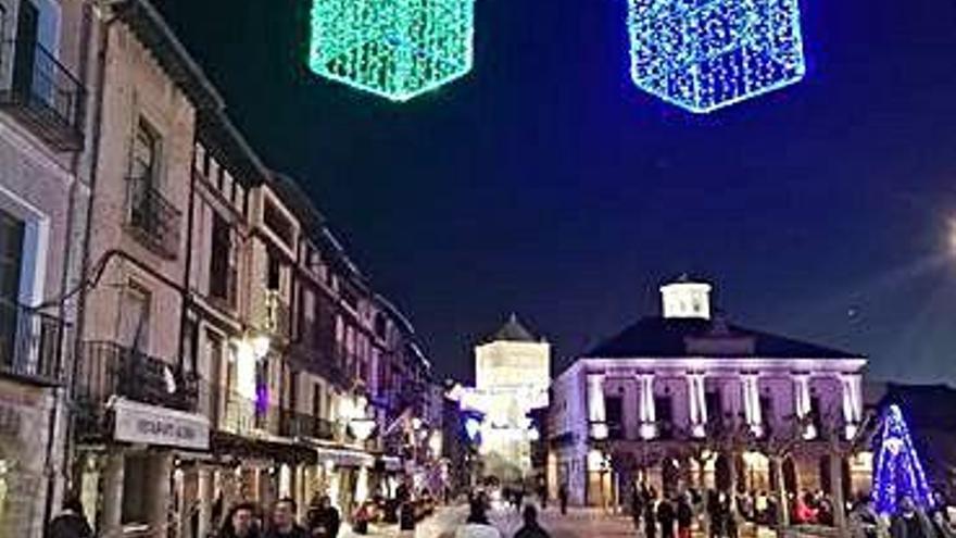 Toresanos pasean por la Plaza Mayor iluminada con cajas de regalo.