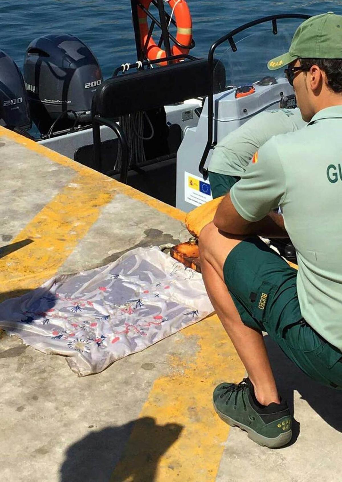 La sábana bordada que contenía restos óseos, ayer, sobre el muelle de Calpe.