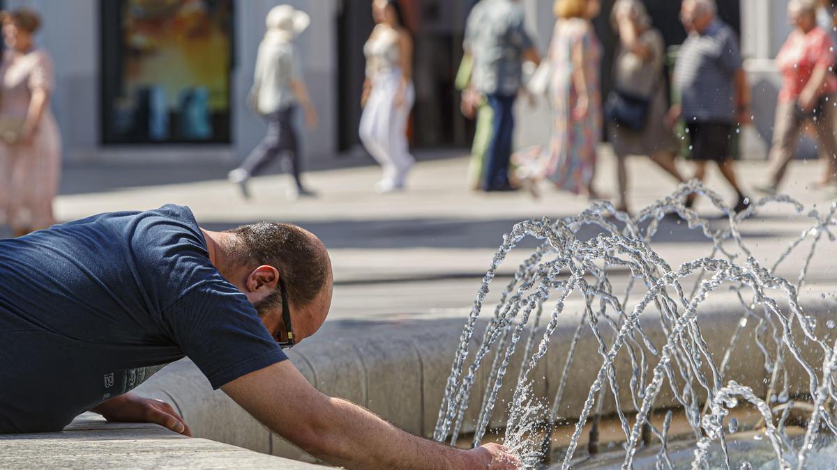 Una persona se refresca en la fuente de la Plaza España
