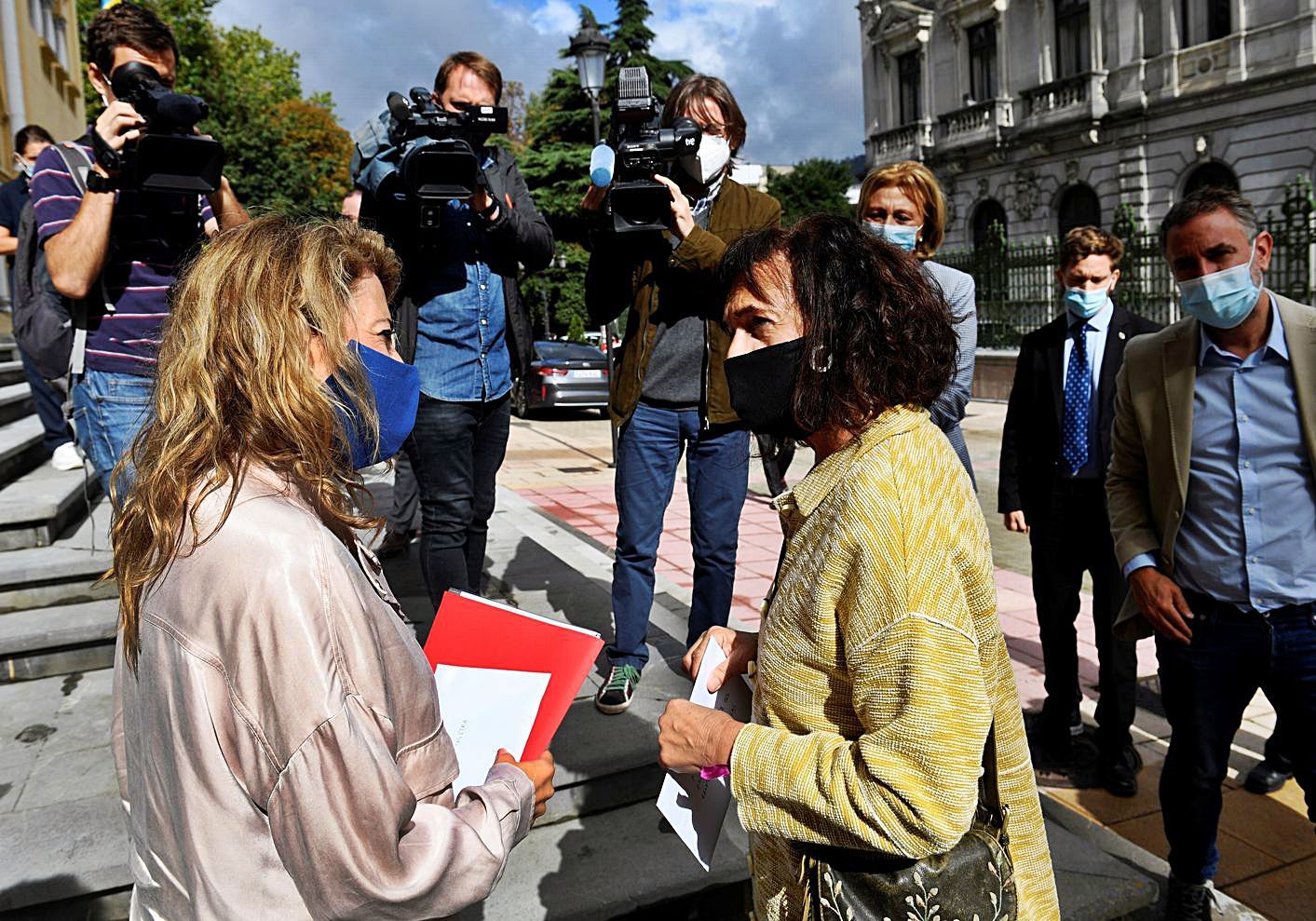 Una representante de la plataforma contra la Ronda Norte de Oviedo entrega un documento a la ministra Raquel Sánchez (a la izquierda), ayer, a las puertas de la Presidencia del Principado. | Efe