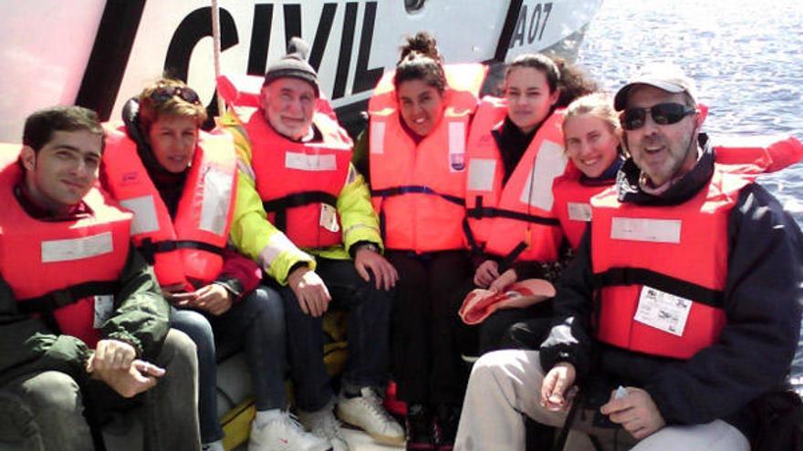 Miembros de la expedición, en el barco, con la nave de la Guardia Civil del Mar, detrás.