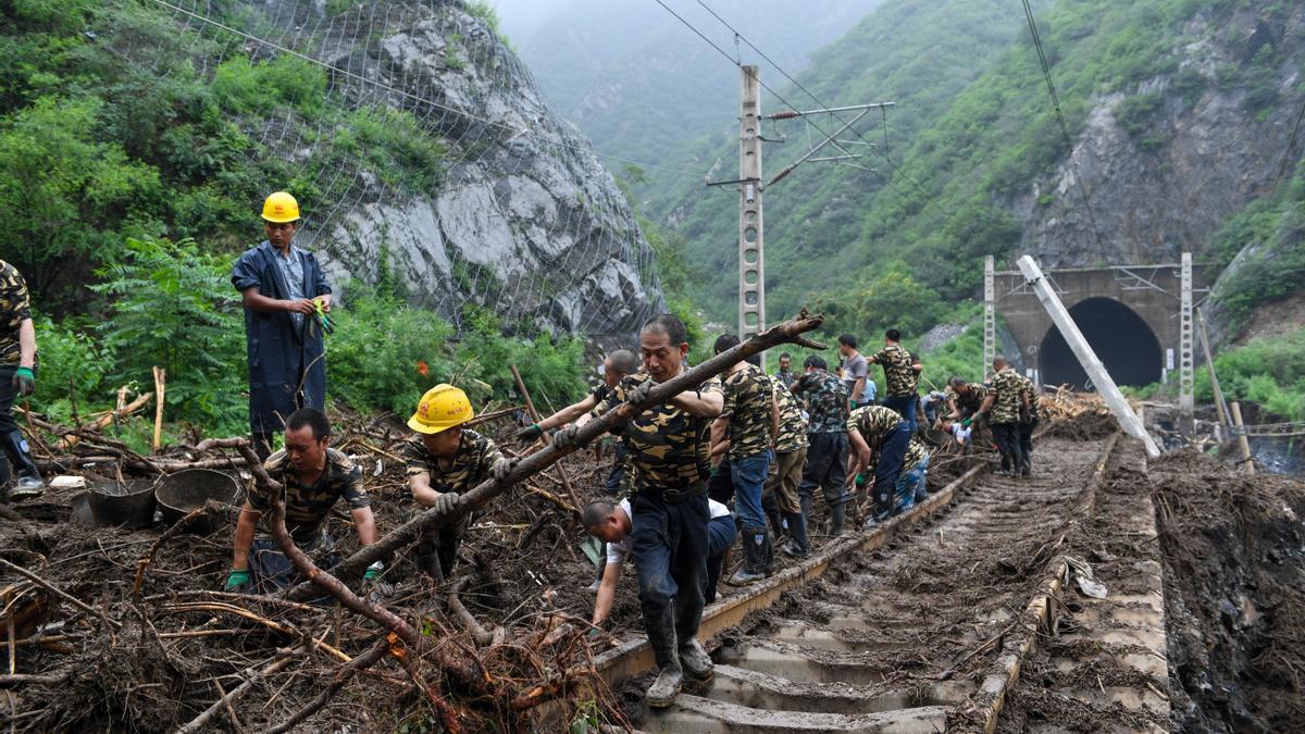 Trabajadores ferroviarios retiran árboles caídos sobre las vías del tren, tras el paso del tifón Doksuri, en Pekín.