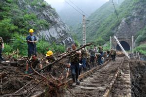 Trabajadores ferroviarios fueron registrados este lunes, 1 de agosto, al retirar árboles caídos sobre las vías del tren, tras el paso del tifón Doksuri, en la aldea de Shuiyuzui, en el distrito de Mentougou (Pekín, China)