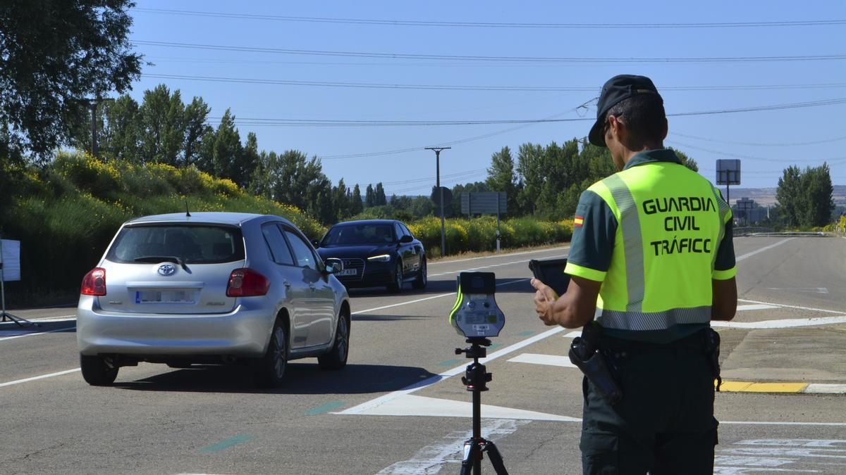 Un agente de la Guardia Civil coloca un radar móvil en una carretera secundaria.