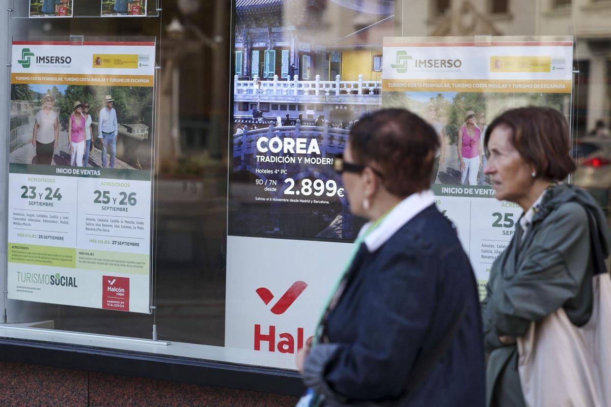 Dos mujeres pasan delante de una agencia de viajes que oferta el programa del Imserso.