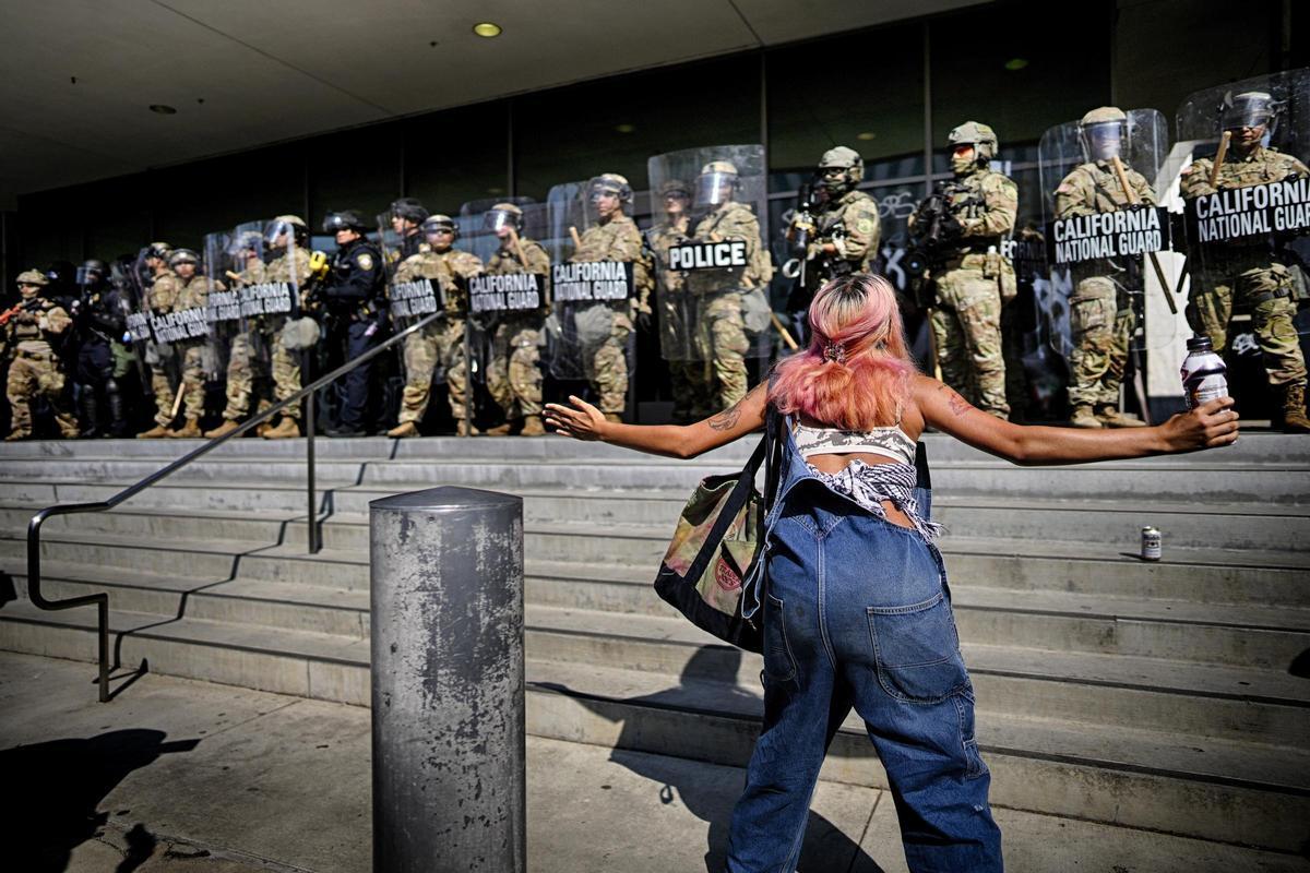 Una mujer protesta ante un cordón policial armado frente a una institución en Los Ángeles.