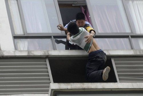 A police officer grabs a man who tries to jump off the seventh floor of a hotel, in Chengdu