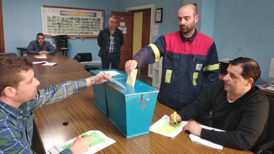 Un trabajador de Alcoa deposita su voto ante varios miembros del comité.