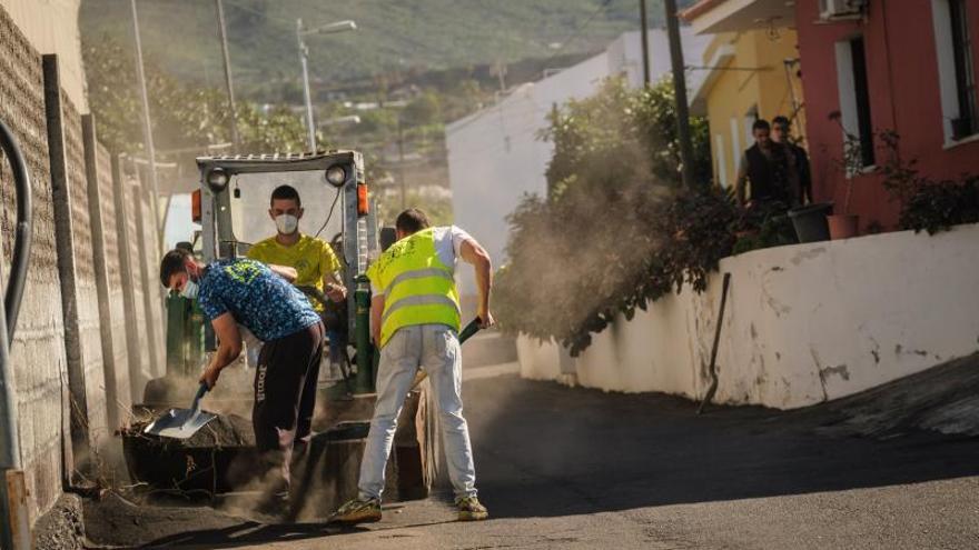 Unos operarios limpian la ceniza acumulada en un camino.