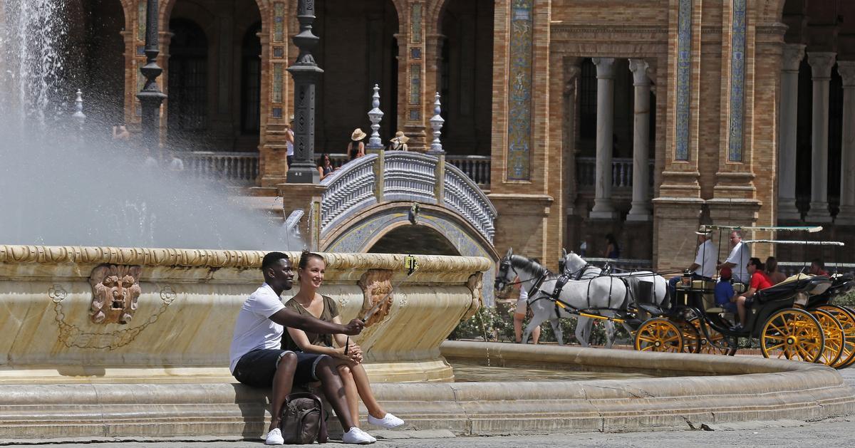 Unos turistas se hacen un selfi en una fuente de la Plaza de España en Sevilla