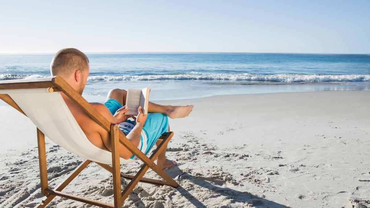 Un hombre leyendo un libro en la playa