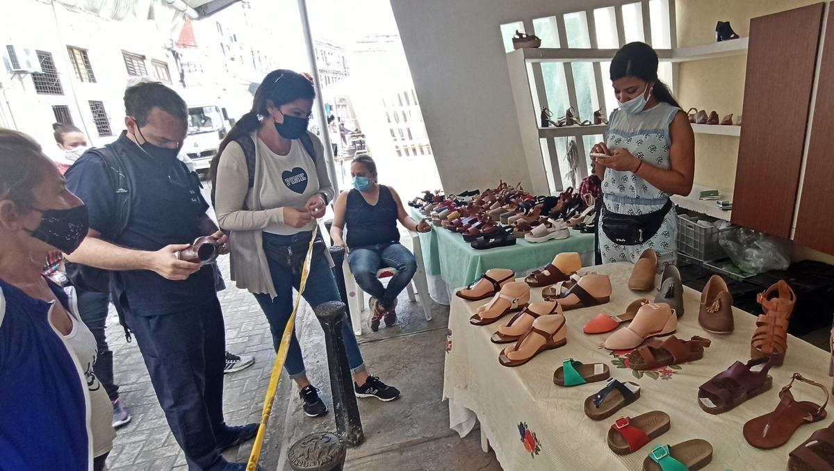 Varias personas miran modelos en un puesto de venta de sandalias de la capital cubana.