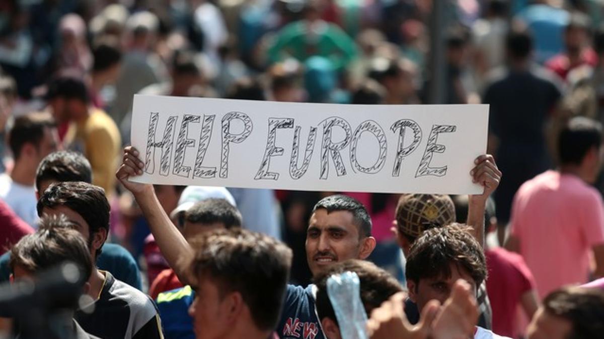 Un inmigrante se manifiesta con una pancarta en la que se lee &quot;Ayúdanos Europa&quot; pidiéndo a las autoridades Húngaras que permitan a los refugiados viajar hacia la Europa Occidental, tras varios polémicos días con las estaciones de trenes cerradas y ca