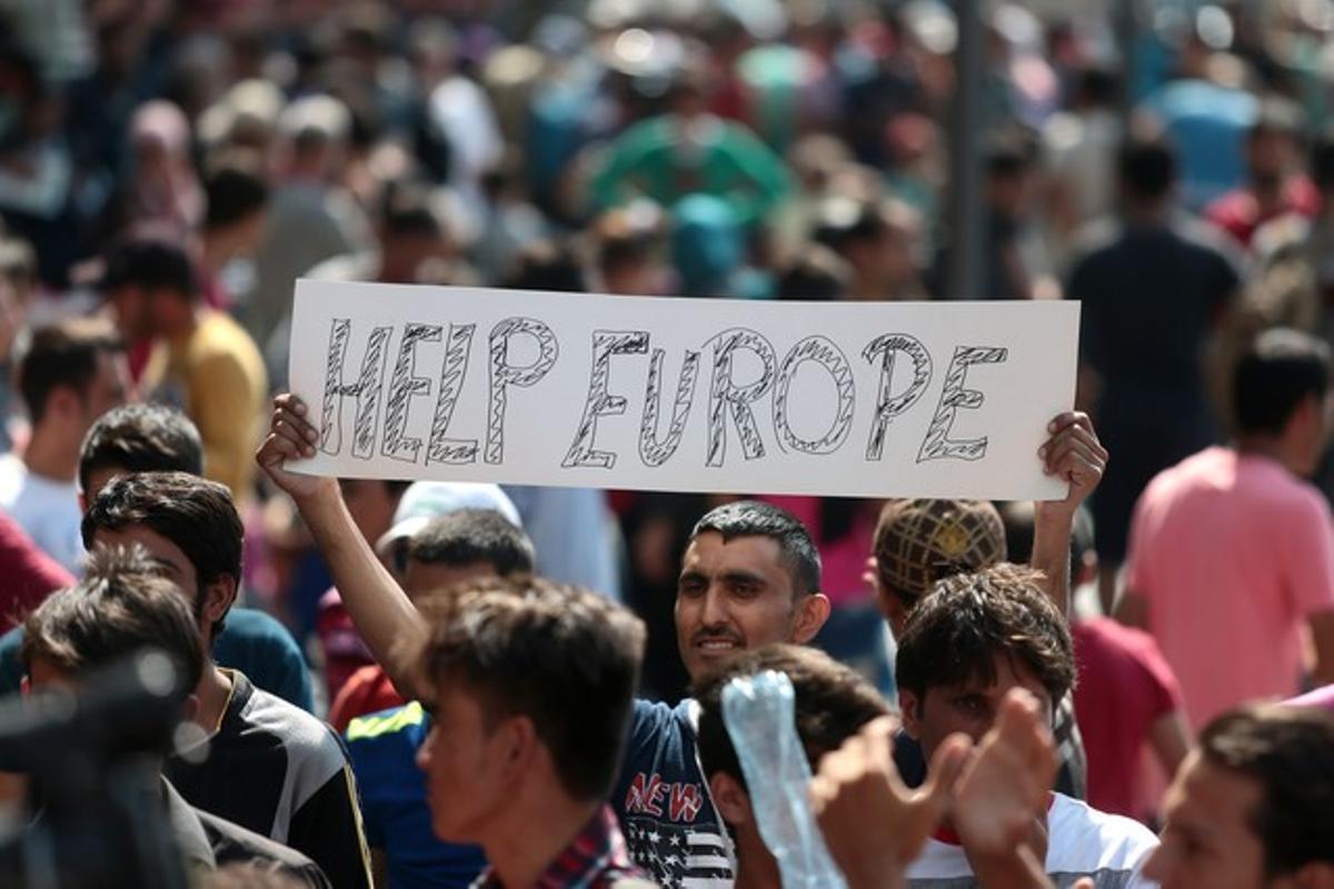 Un immigrant es manifesta amb una pancarta en què es llegeix ’Ajuda’ns, Europa’ demanant a les autoritats hongareses que permetin als refugiats viatjar cap a l’Europa Occidental, després de diversos dies polèmics amb les estacions de trens tancades.