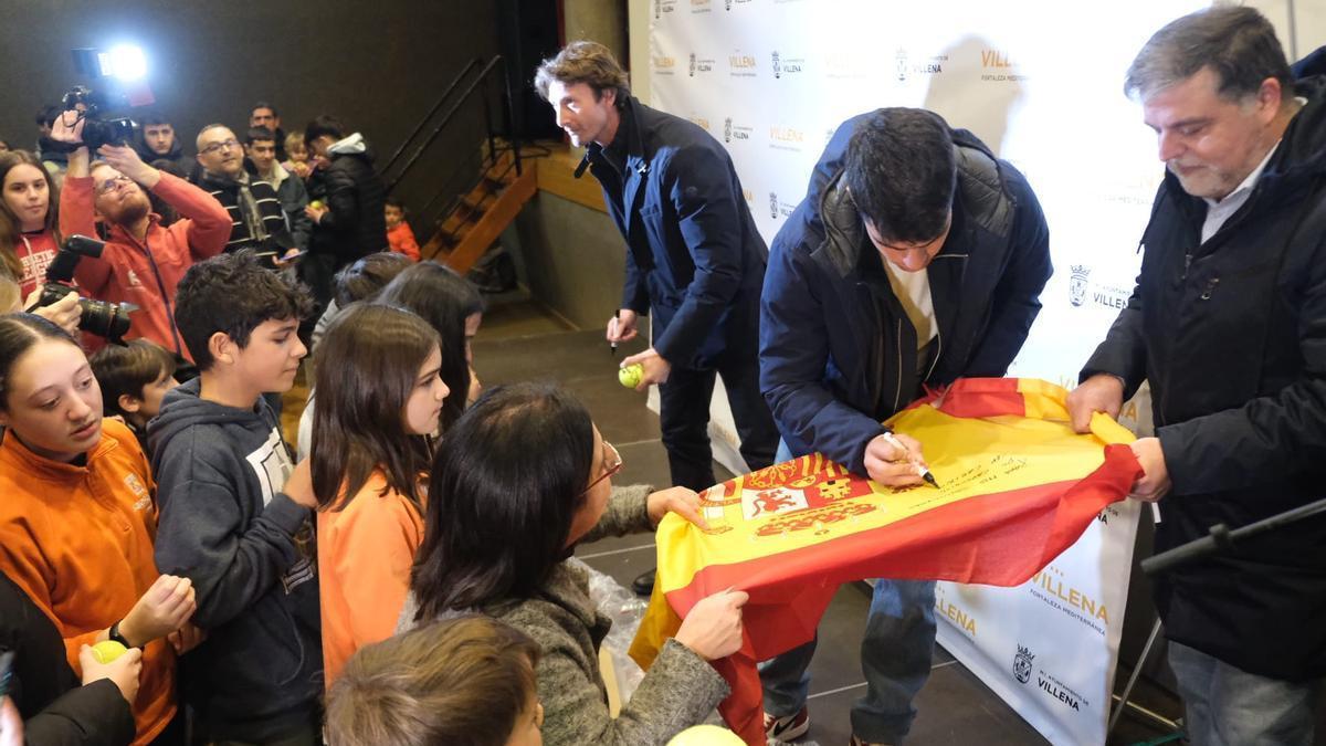 Alcaraz firmando una bandera de España que le sostenía el alcalde y Ferrero lanzando pelotas al público. / ÁXEL ÁLVAREZ