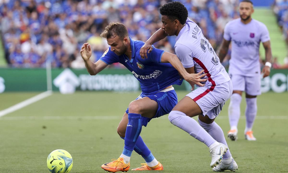 El delantero del Getafe, Borja Mayoral (i), protege el balón ante el defensa del FC Barcelona, Alex Balde.