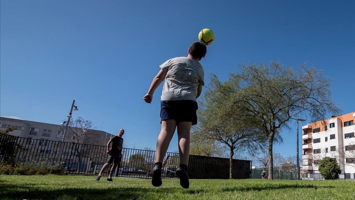 Un padre y un hijo juegan a fútbol  en un parque de Palma, aprovechando las nuevas franjas de salida