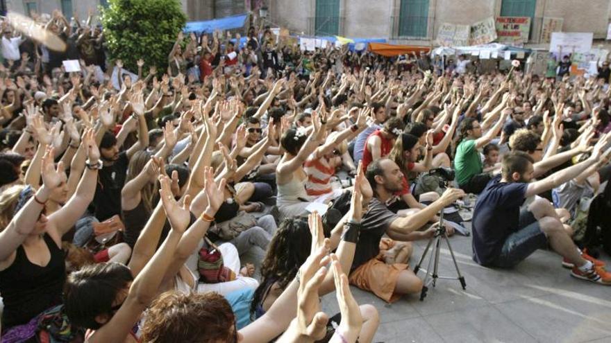 Indignados del 15M levantan las manos durante la acampada que se organizó en la Glorieta de España, en Murcia.