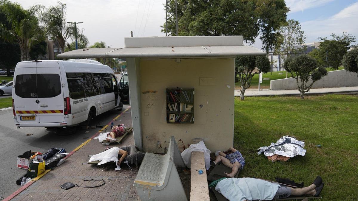 Civiles asesindos por militantes palestinos yacen en la calle cubiertos por sábanas en la localidad de Sderot, en Israel. /