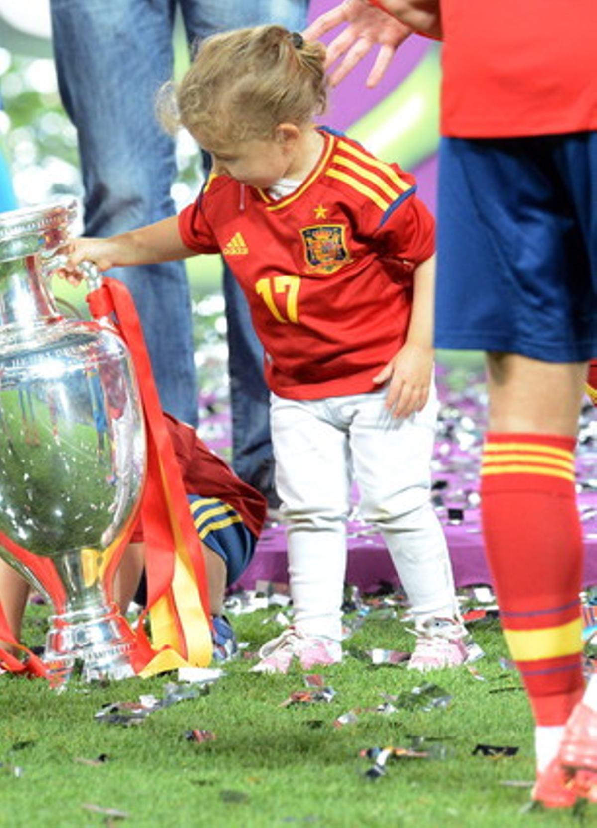 La hija Arbeloa, Alba, trata de levantar el trofeo de la Eurocopa 2012.