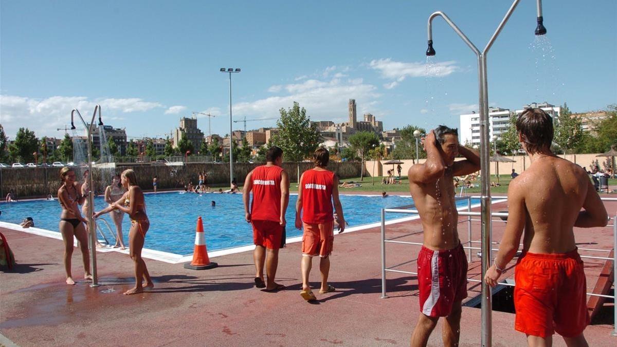 Unos jóvenes se refrescan en una piscina pública.