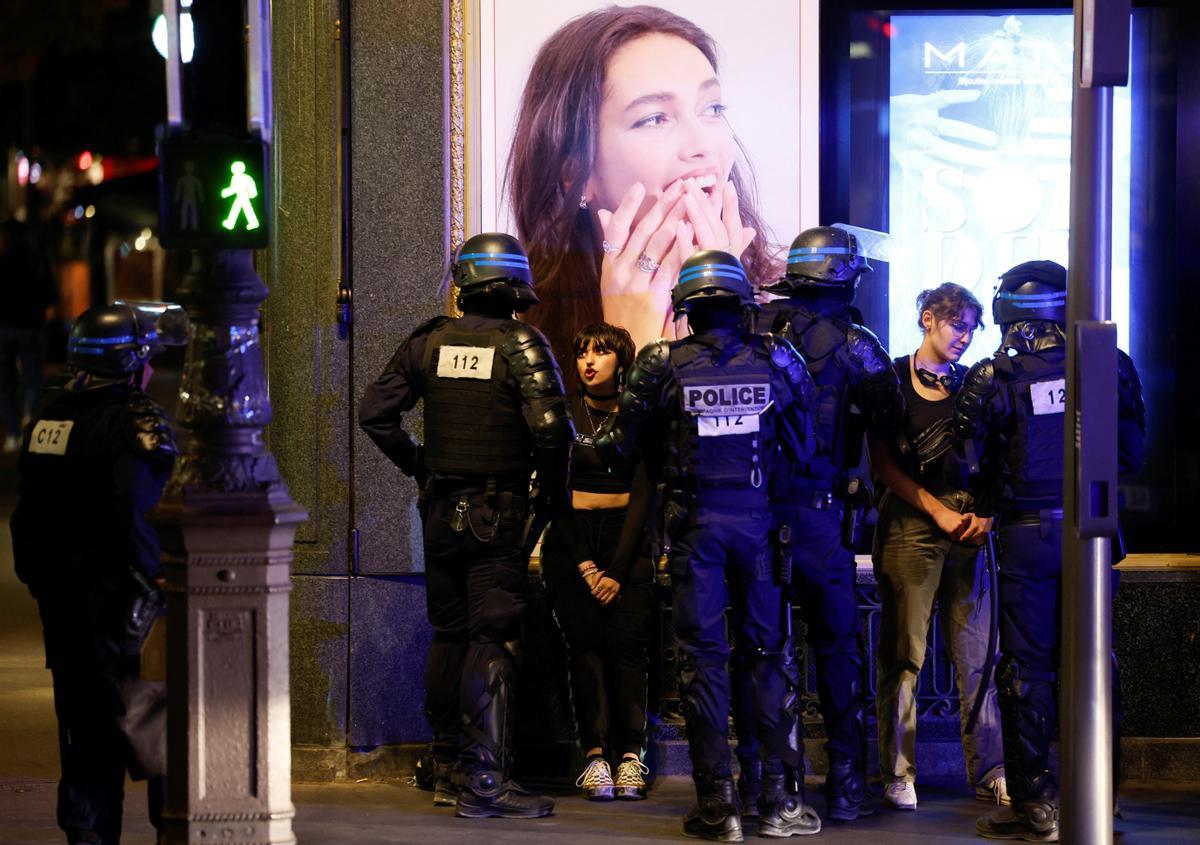 Los disturbios se extienden por Francia en la cuarta noche de protestas. Oficiales de policía hablan con mujeres mientras la gente protesta cerca de la Ópera Garnier, en París