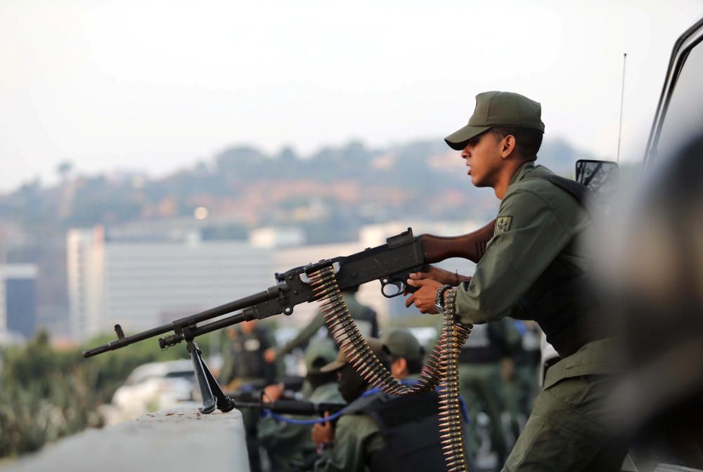 A military member aims a weapon near the ...