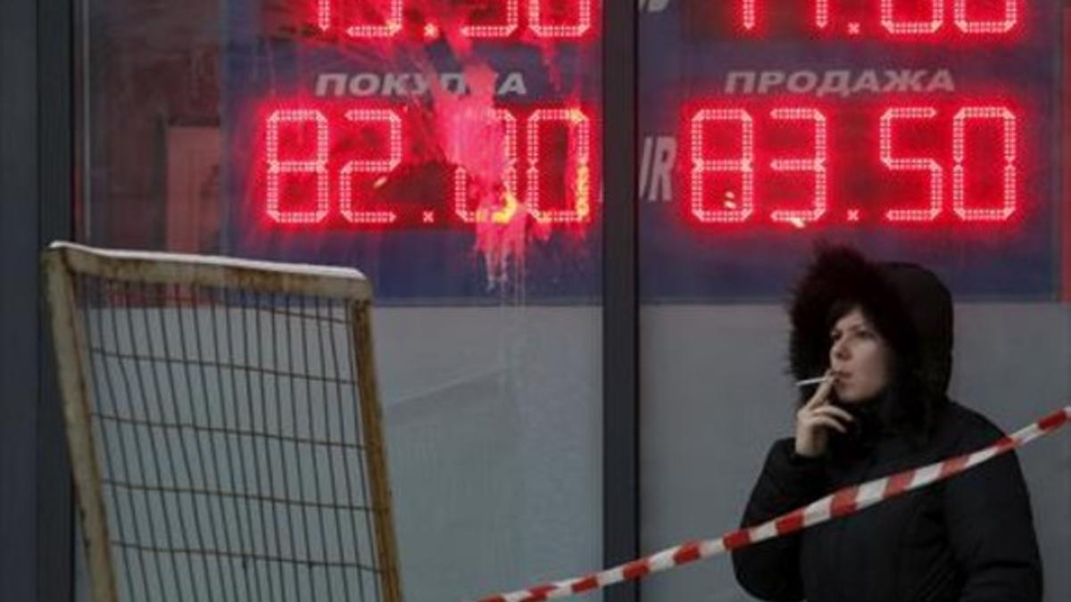 Incertidumbre 8Una mujer, ante un panel que muestra el cambio del rublo ante el euro y el dólar, en Moscú.