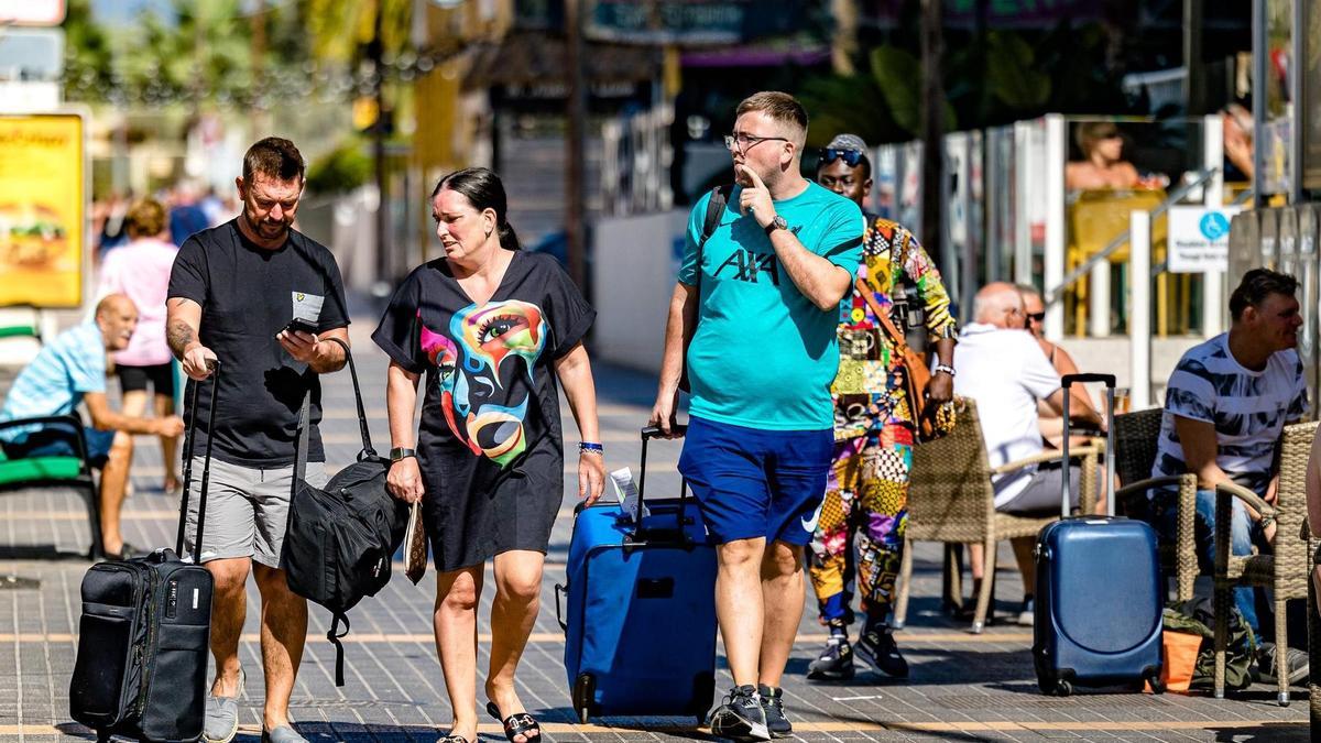 Turistas británicos en una terraza y con maletas por una calle de Benidorm.