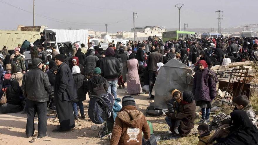 Familias huidas de los barrios del noroeste de Alepo, esperando la llegada de autobuses para trasladarse a otras zonas de la ciudad siria.