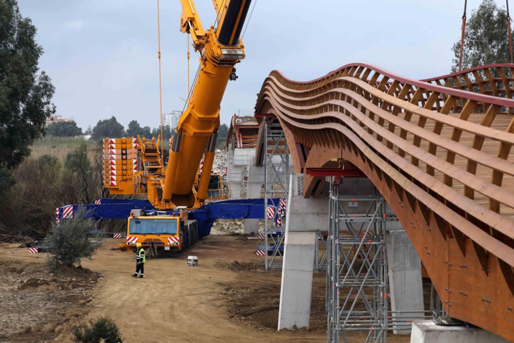 La instalación del último tramo del puente de madera sobre el río Guadalhorce ha comenzado este martes.