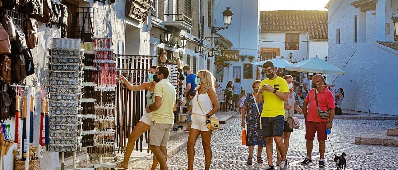 Turistas, en una de las calles del municipio, junto a una de las tiendas que permanecen abiertas.