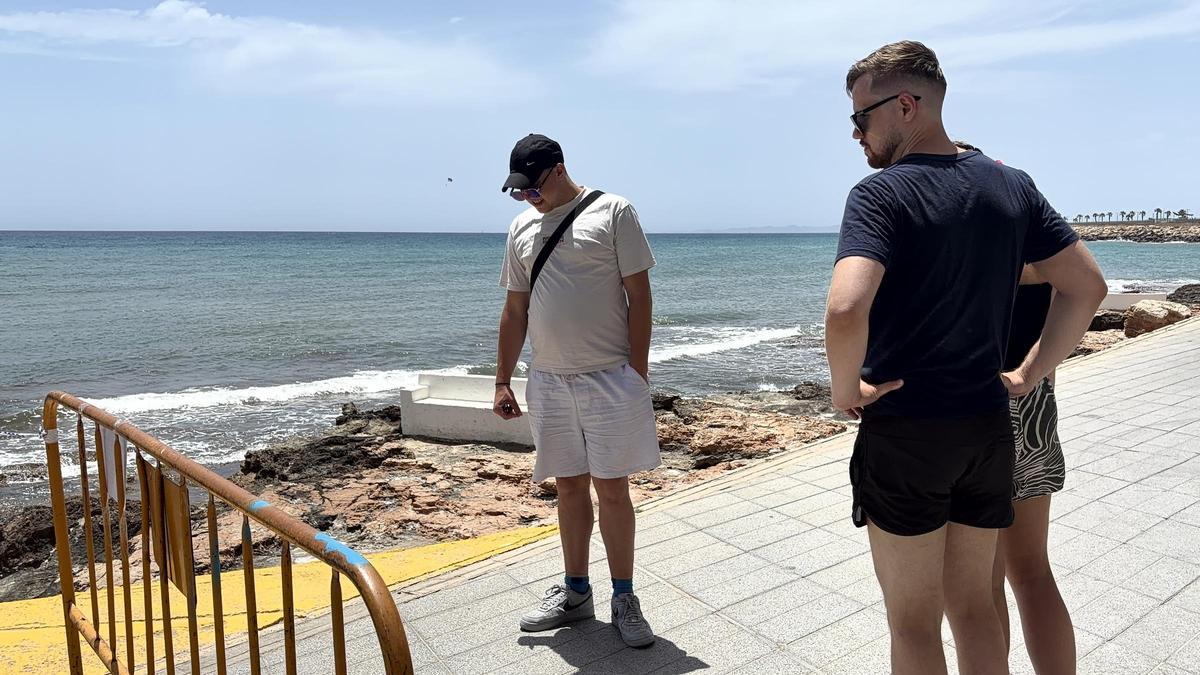 Turistas observan el cartel indicativo del cierre de la zona de baño difundido en castellano e inglés