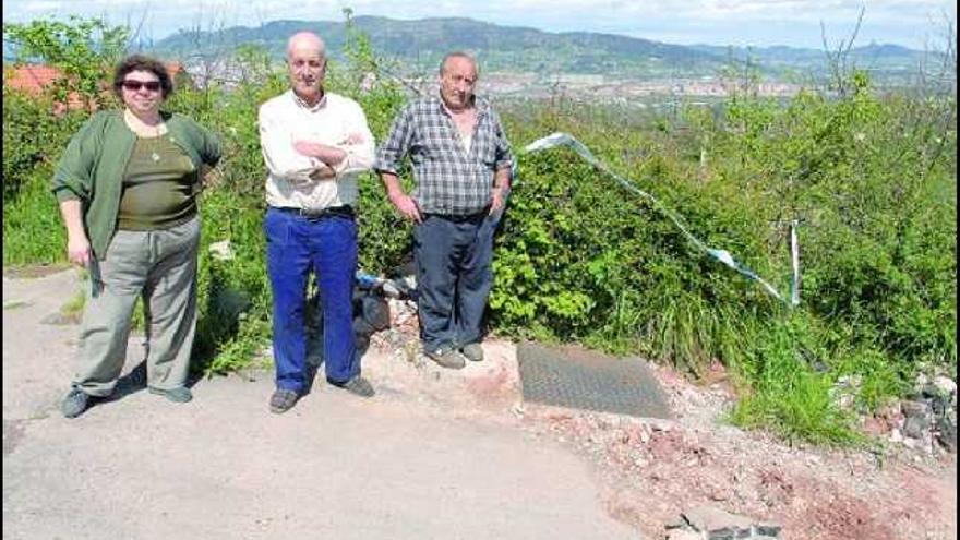 Fuensanta Santos, Enrique Alonso y Constantino Argüelles, junto a uno de los baches de la carretera.