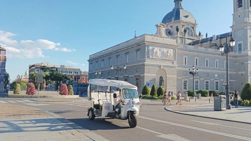 Un tuk tuk circula frente a la Catedral de la Almudena