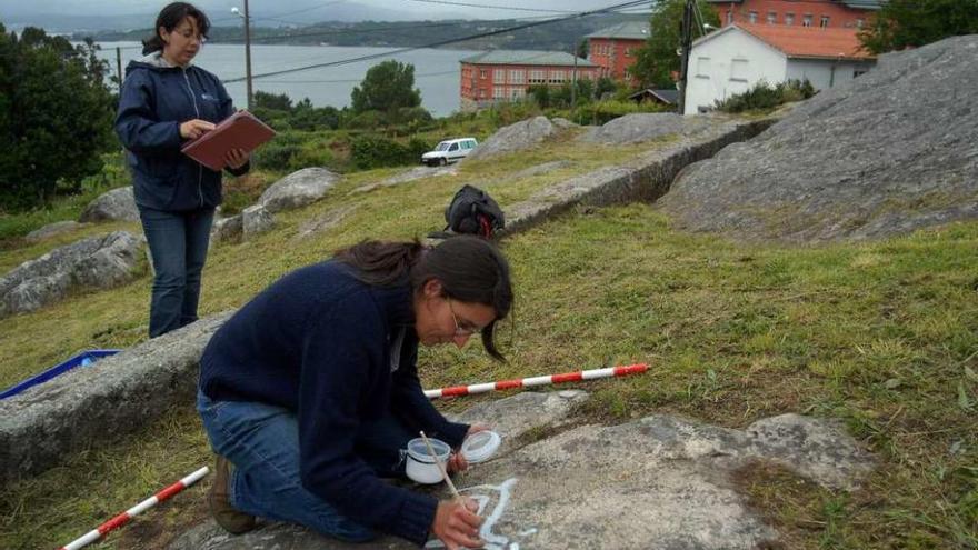 Dos arqueólogas realizan trabajos de conservación en los petroglifos de Bamio. // Iñaki Abella