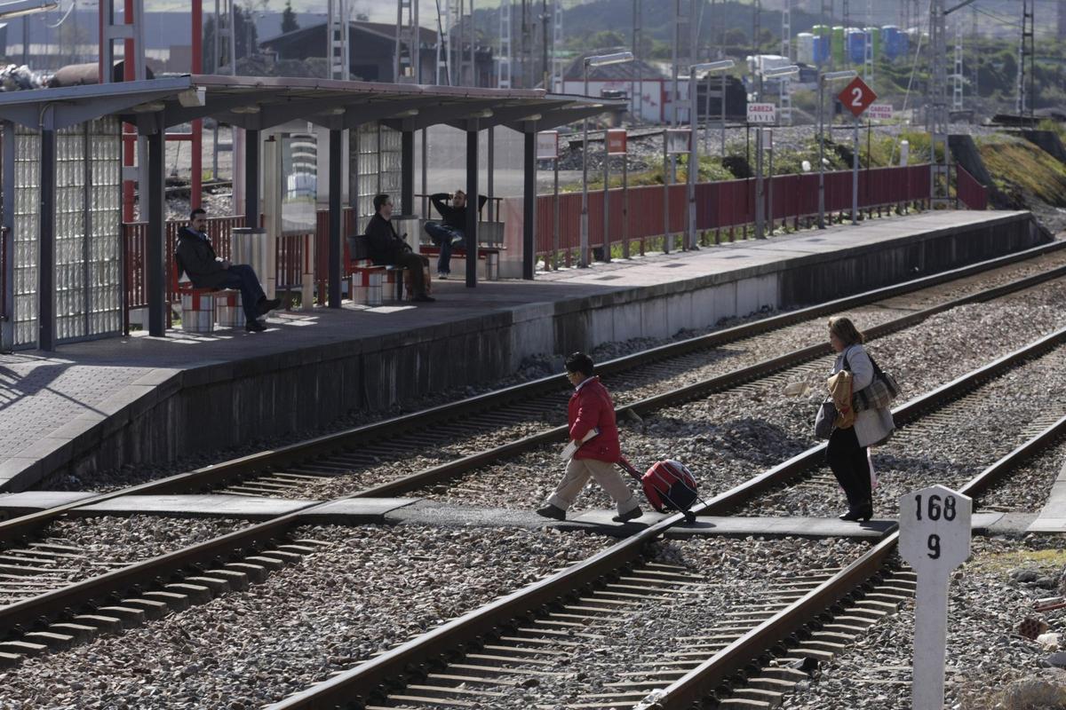 Viajeros cruzan las vías desde la estación de Calzada de Asturias al apeadero.