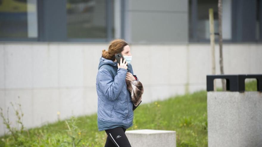 Una mujer pasea por la calle con mascarilla.