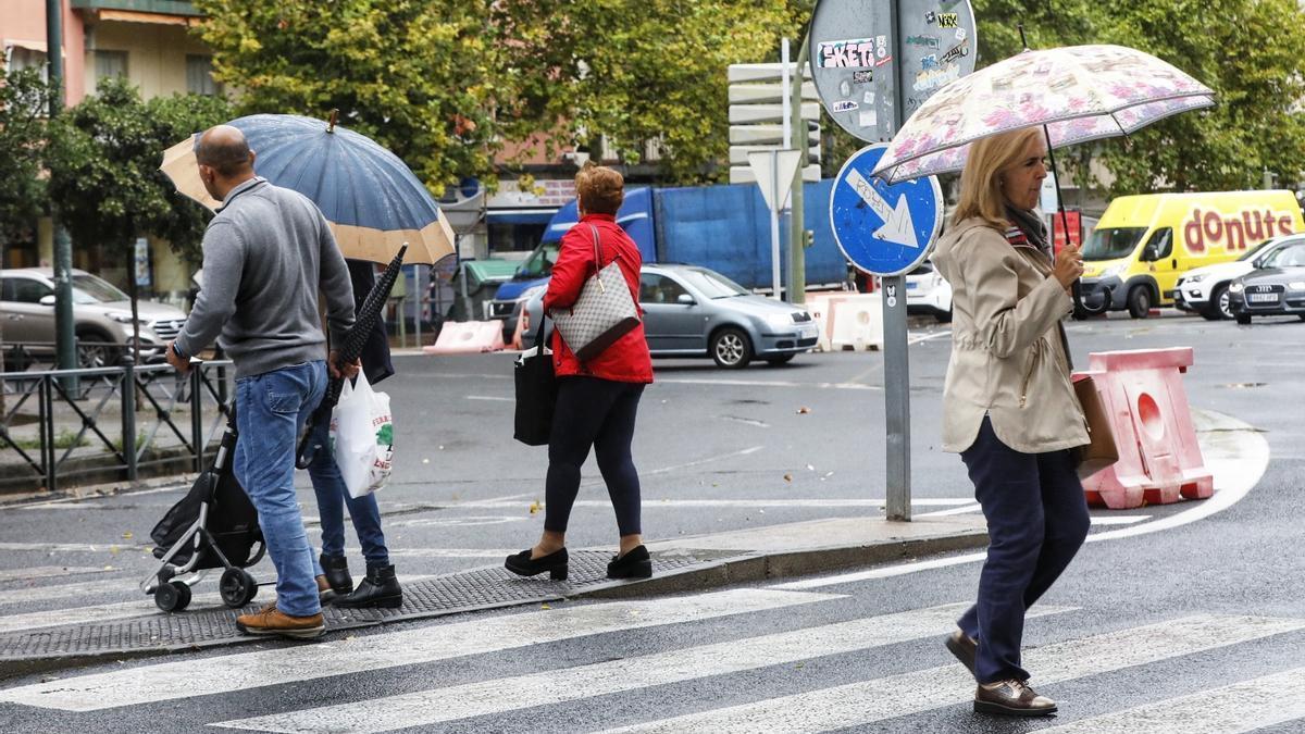 Peatones con paraguas en el centro de Cáceres.
