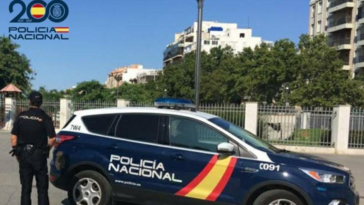 Un agente de la Policía Nacional en Palma, junto a su coche patrulla.