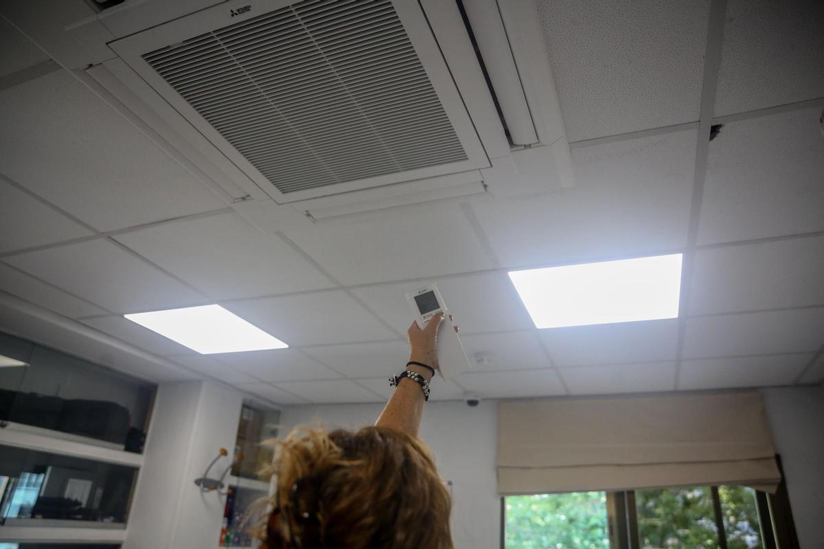 Una mujer enciende el aire acondicionado en una oficina en una fotografía de archivo