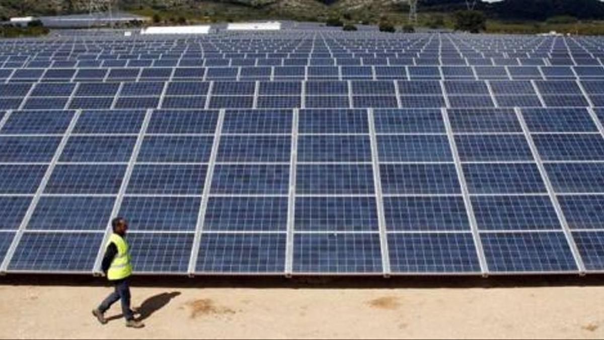 Un operario pasa ante una instalación de energía renovable en una planta fotovoltaica ubicada en la Comunitat Valenciana.