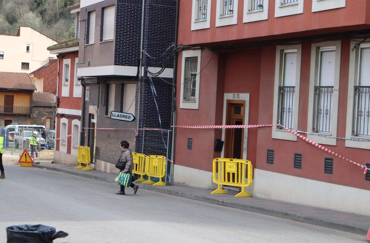 Una vecina sale con enseres de su domicilio afectado por la explosión tras ser autorizada a acceder al inmueble.