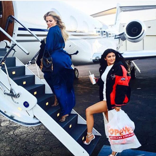 Khloé Kardashian y Kylie Jenner subiendo a un avión con pollo frito de Popeyes