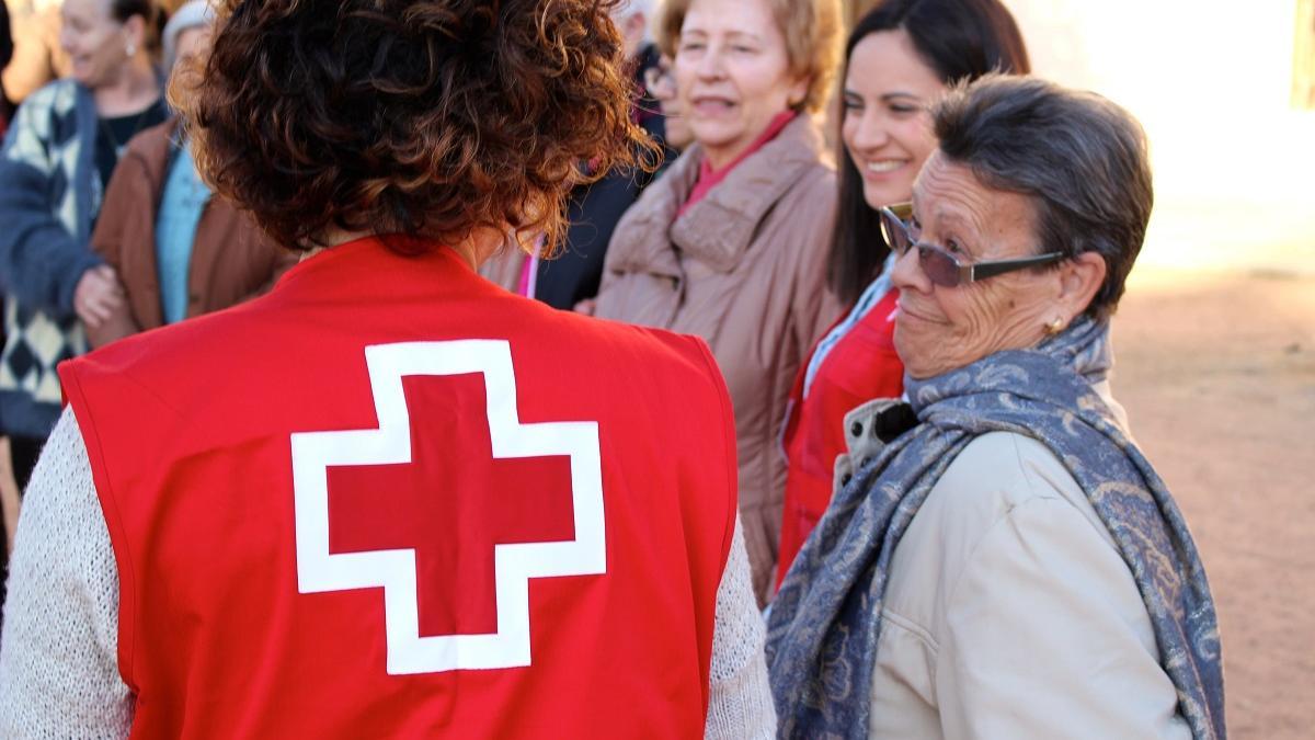 Una voluntaria de Cruz Roja junto a un grupo de personas mayores.