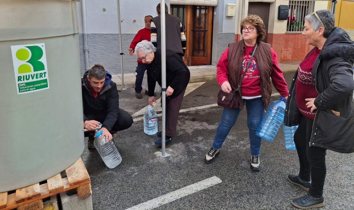 Las vecinas de la Vall de Laguar llenan garrafas en un depósito