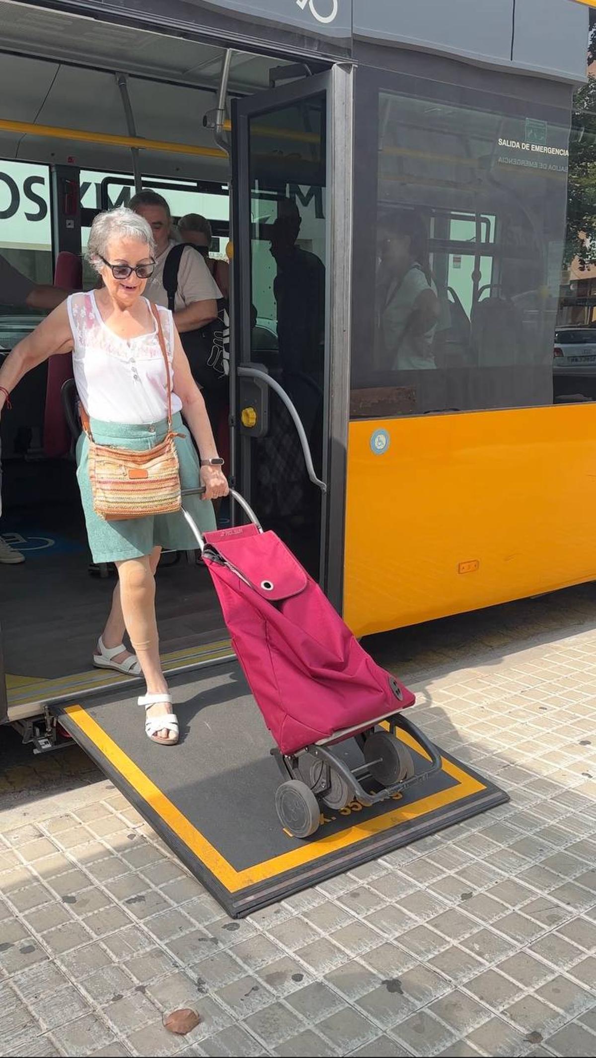 Una usuaria baja por la rampa del autobús con el carro de la compra.